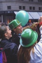 Happy young women with green bowler hats and balloons cheering at St. PatrickÃ¢â¬â¢s Day parade in the streets